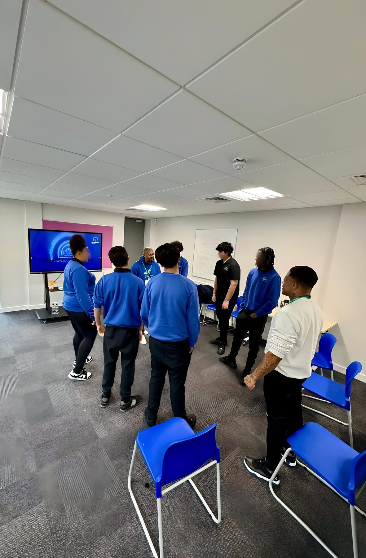 Young people standing together in a group session with a facilitator